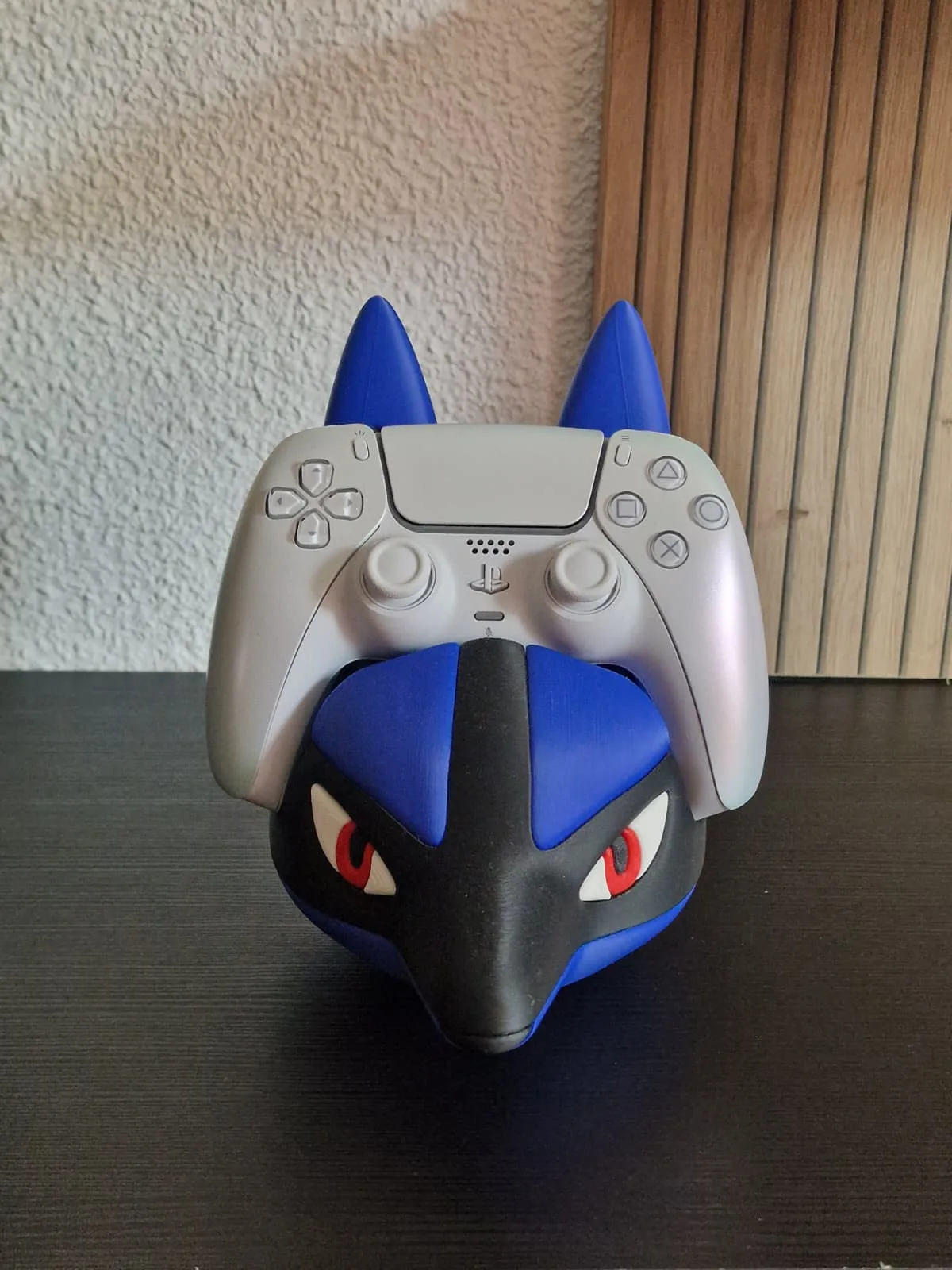 Soporte con forma de cabeza de Lucario sujetando un mando DualSense blanco entre las orejas